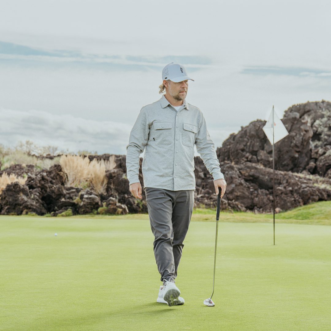 Golfer walking across the green with a putter