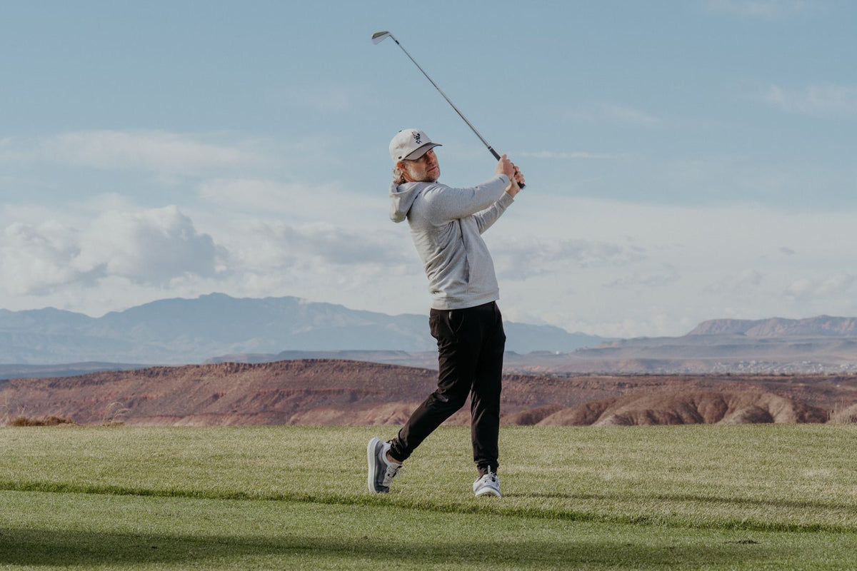 Golfer in TRUE shoes finishing an iron swing on a fairway